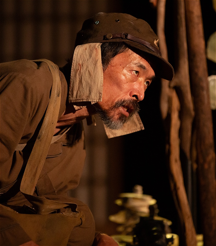 A tired Japanese WWII soldier looks to his left.