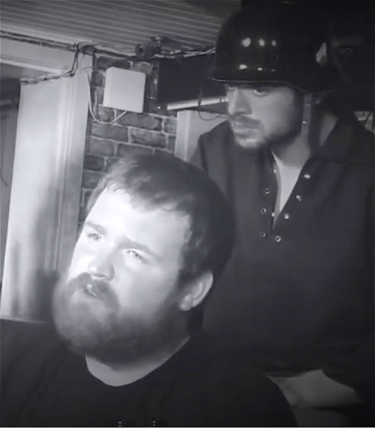 Two men sit in a bar, talking.