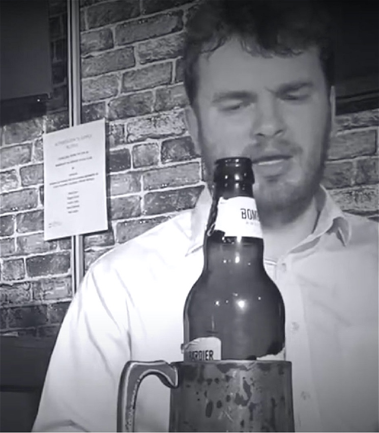 A man sits in the bar, his drink in front of him.
