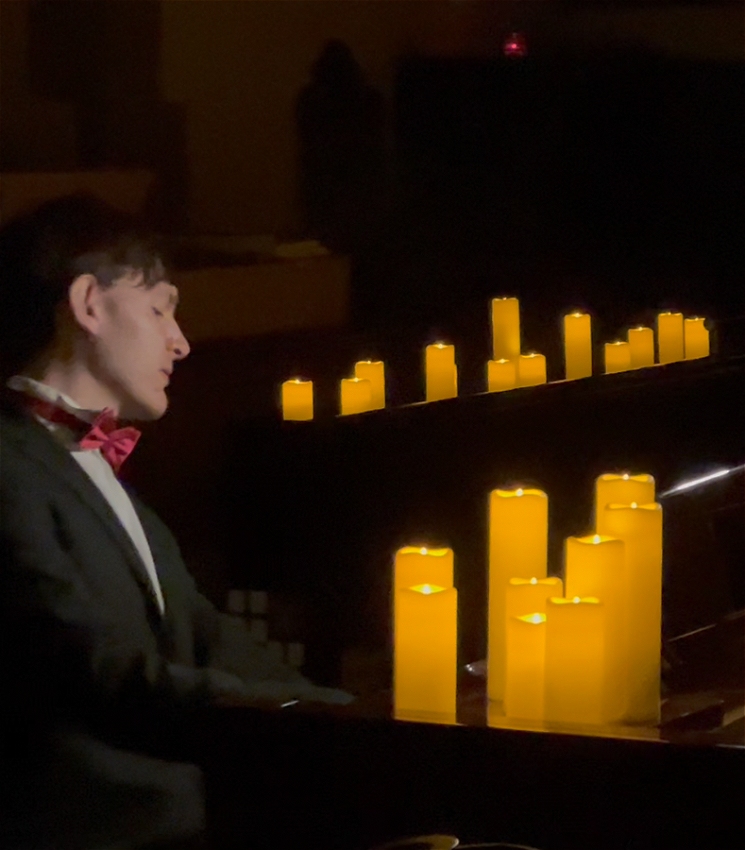 Matthew Shiel playing the piano by candlelight